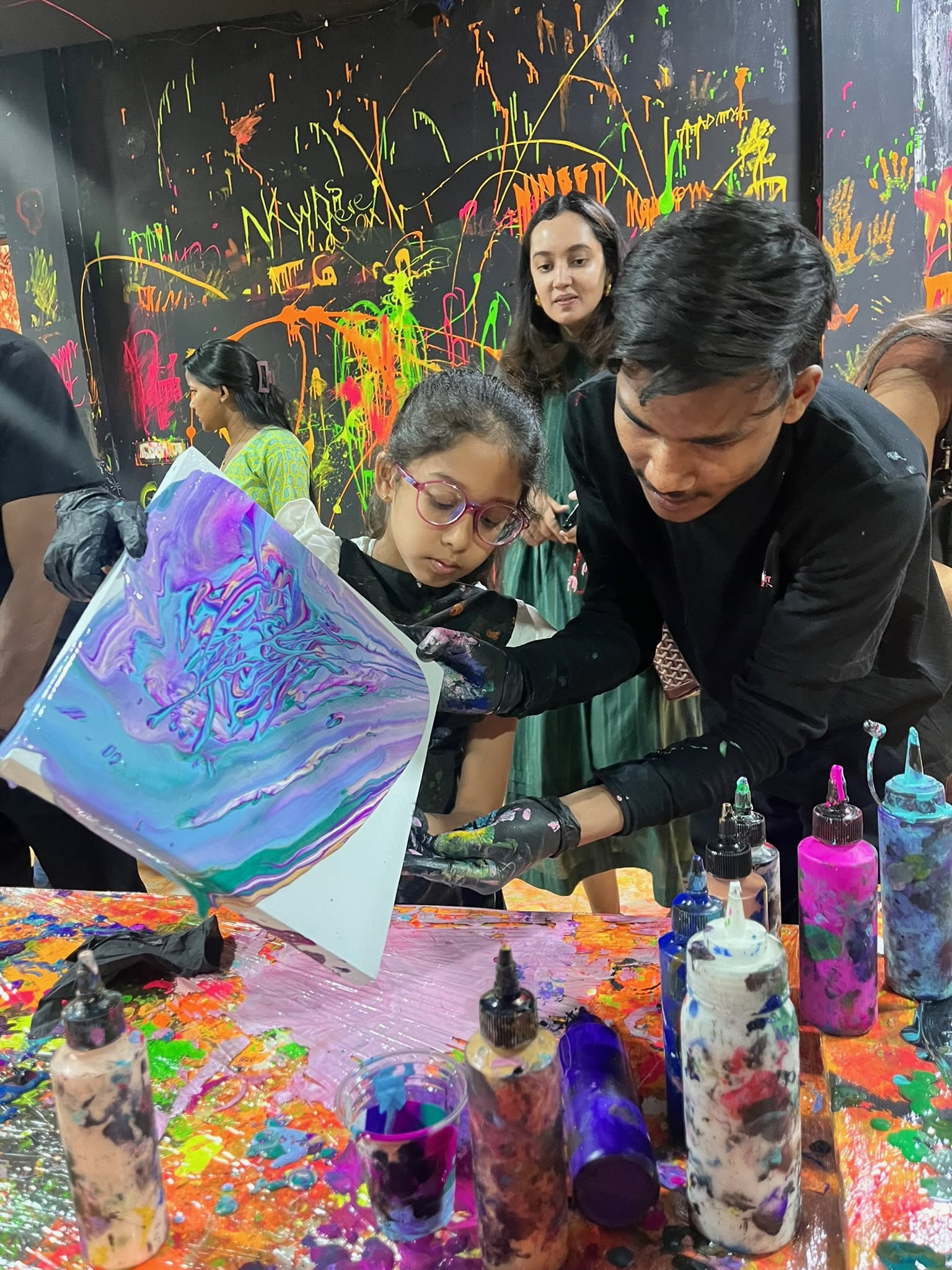 Woman creating colourful acrylic pour fluid art on canvas at Splashit
