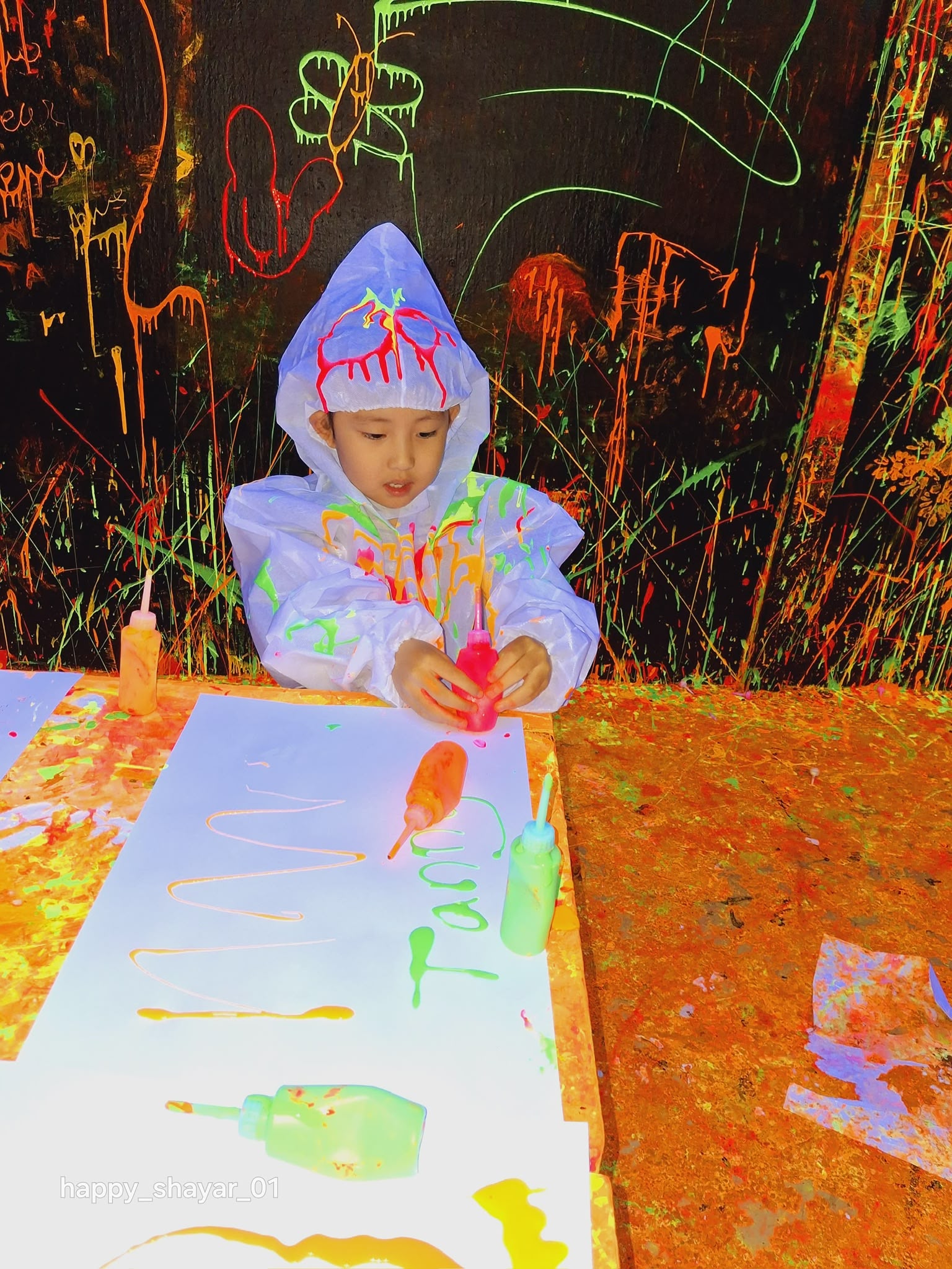 Friends throwing glow-in-the-dark neon paint in Splashit's UV blacklight splatter room