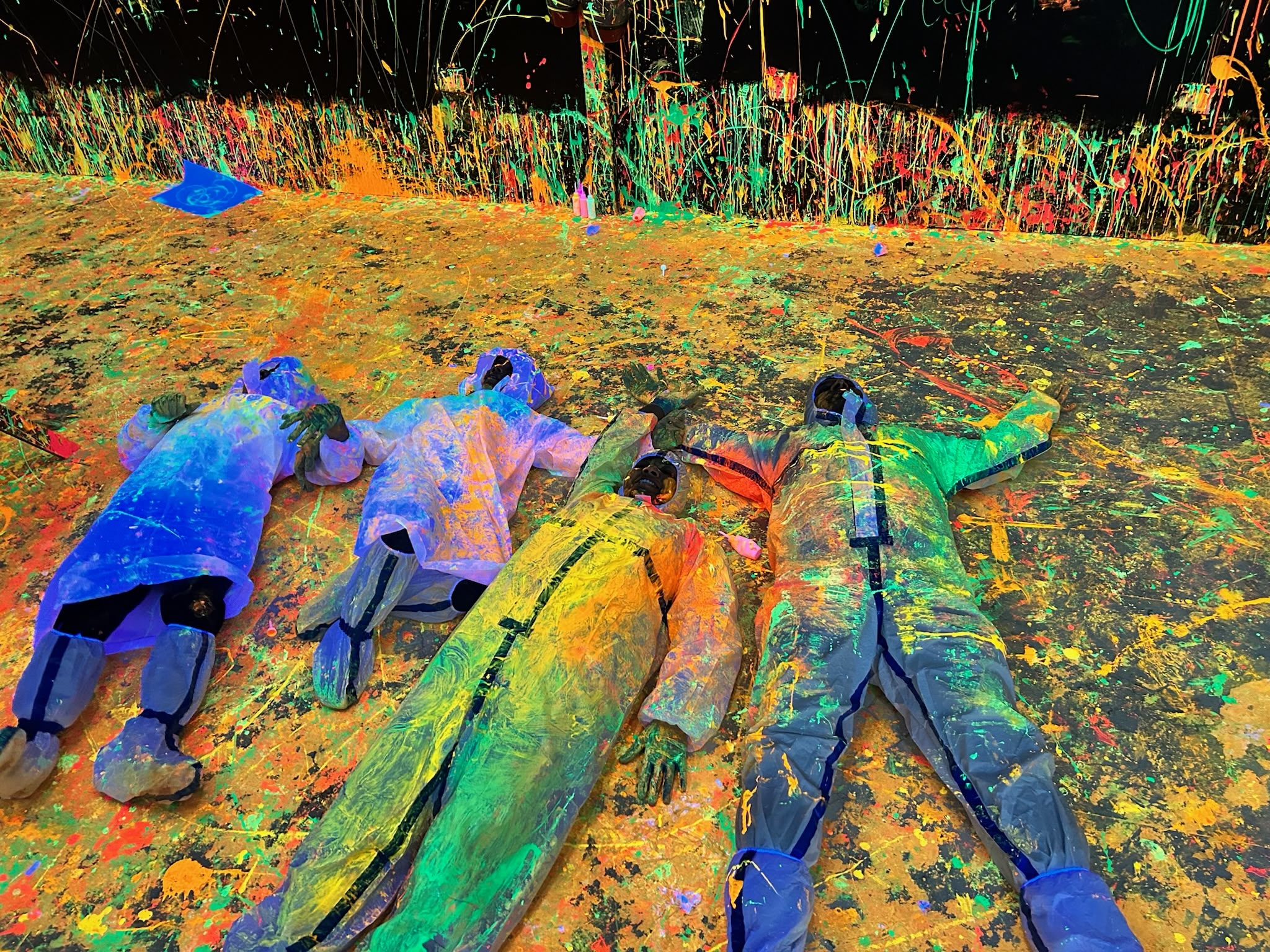 Friends throwing glow-in-the-dark neon paint in Splashit's UV blacklight splatter room